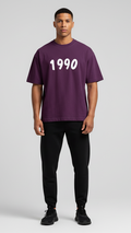 Person wearing a purple t-shirt with '1990' printed on it against a plain background